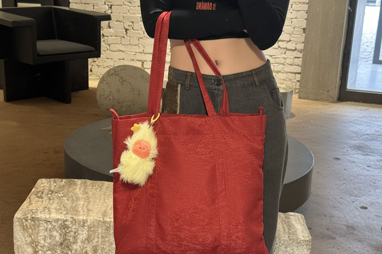 Person holding our year of the fire horse tote bag with a decorative item, wearing our Ju Crop Top and Wang patchwork Denim Pants.